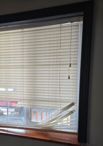 1 of the many broken blinds looking out towards the road.