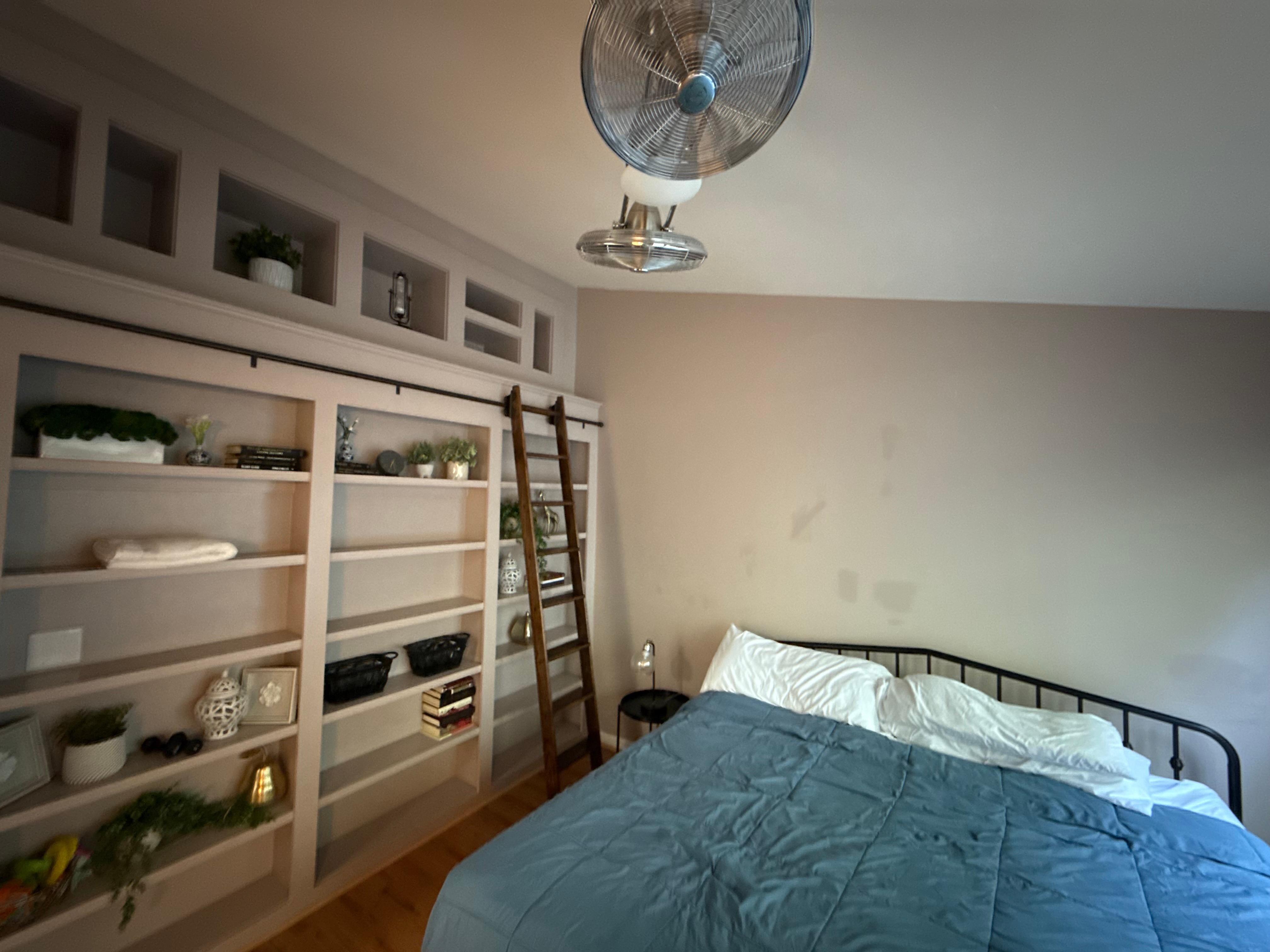 Master bedroom with fans and little bookcase with ladder. 
