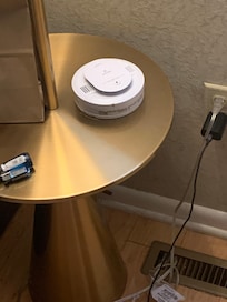 Smoke detector TAPED to bedroom end table.