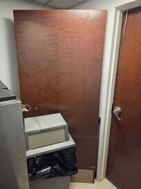 A broken door just hanging out next to the ice machine.