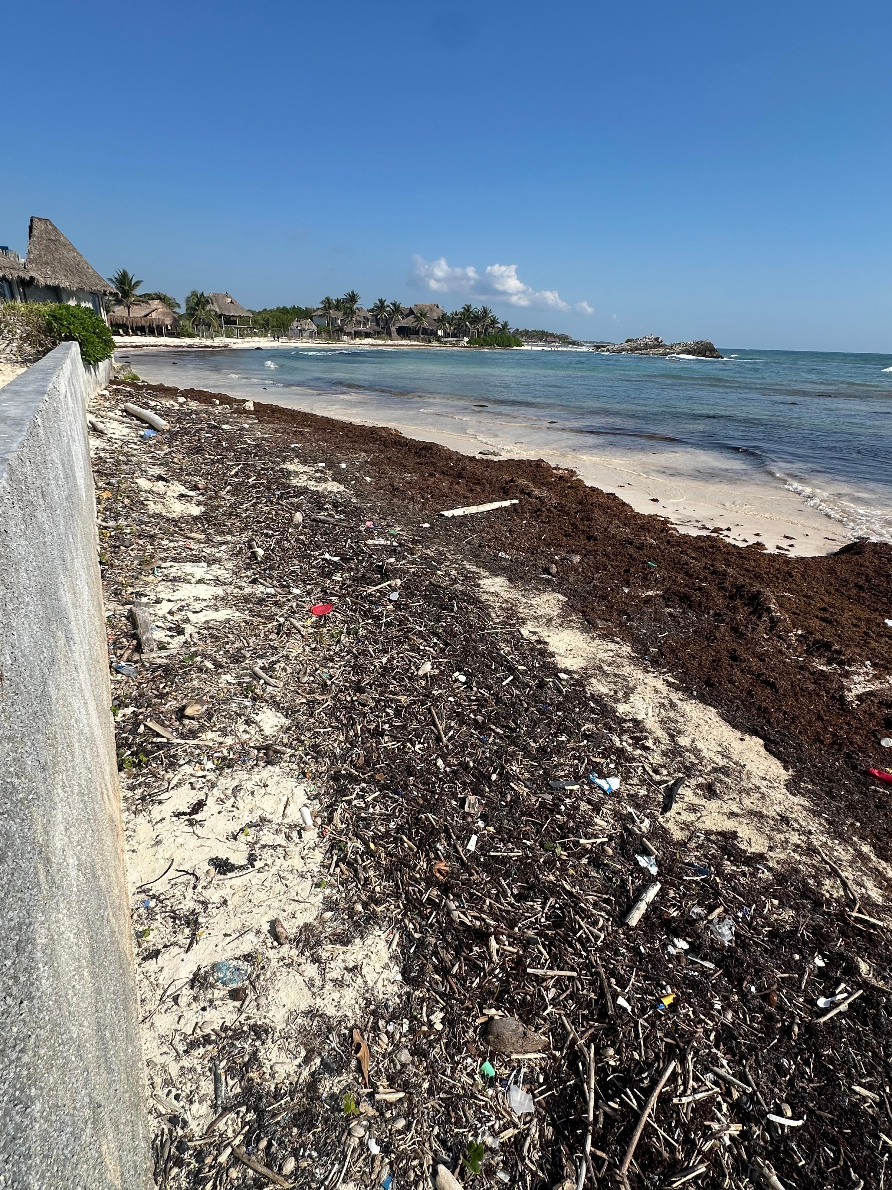 Beach in front of concrete barrier separating room from water 