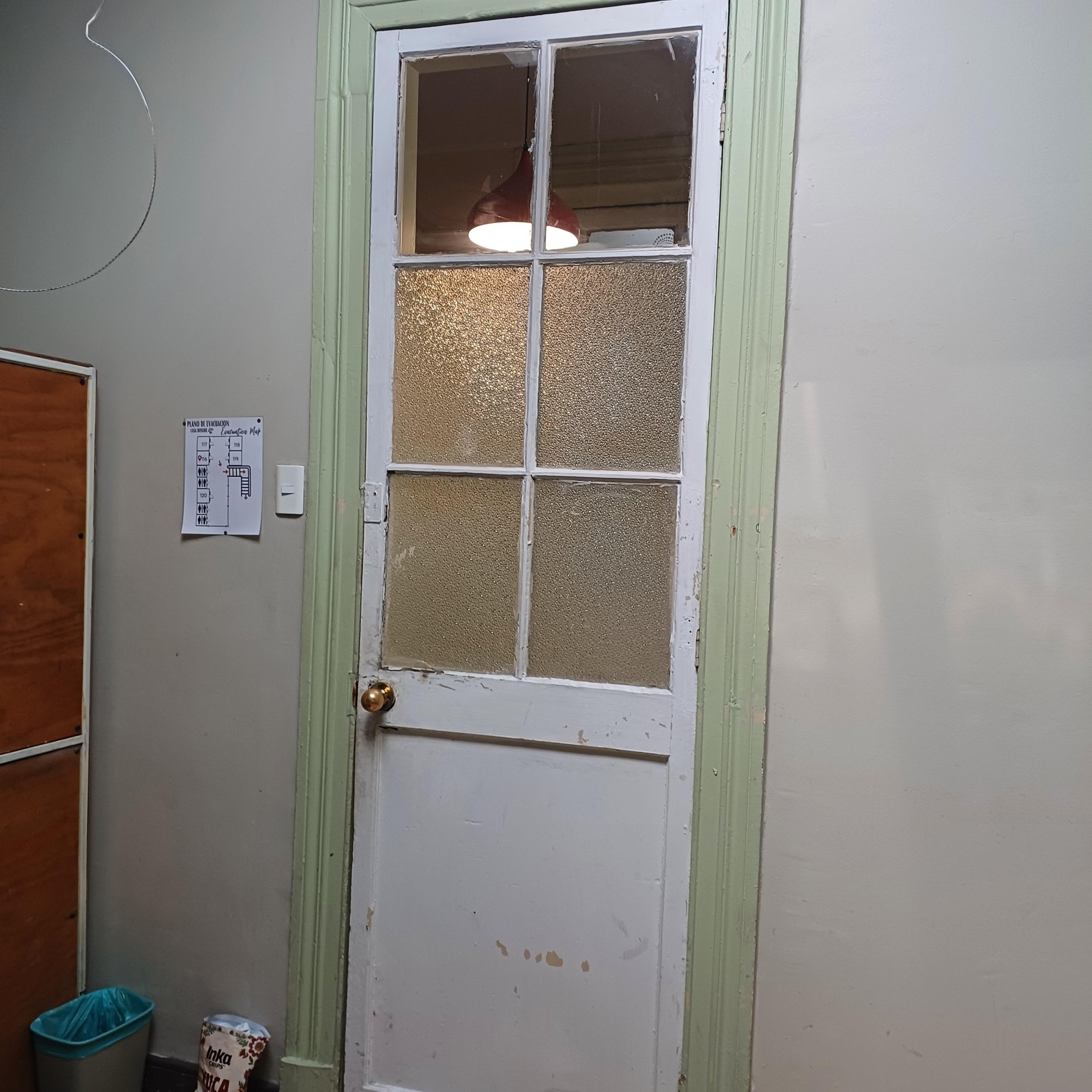 Porta de vidro em frente a uma lâmpada do corredor que fica constantemente acesa.