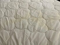 Yellow stains on mattress under sheets.