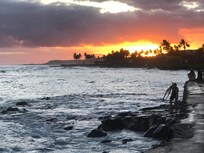 Sunset next to building, watching surfers at same time.