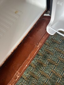 Rotted bottom edge of refrigerator with pieces falling