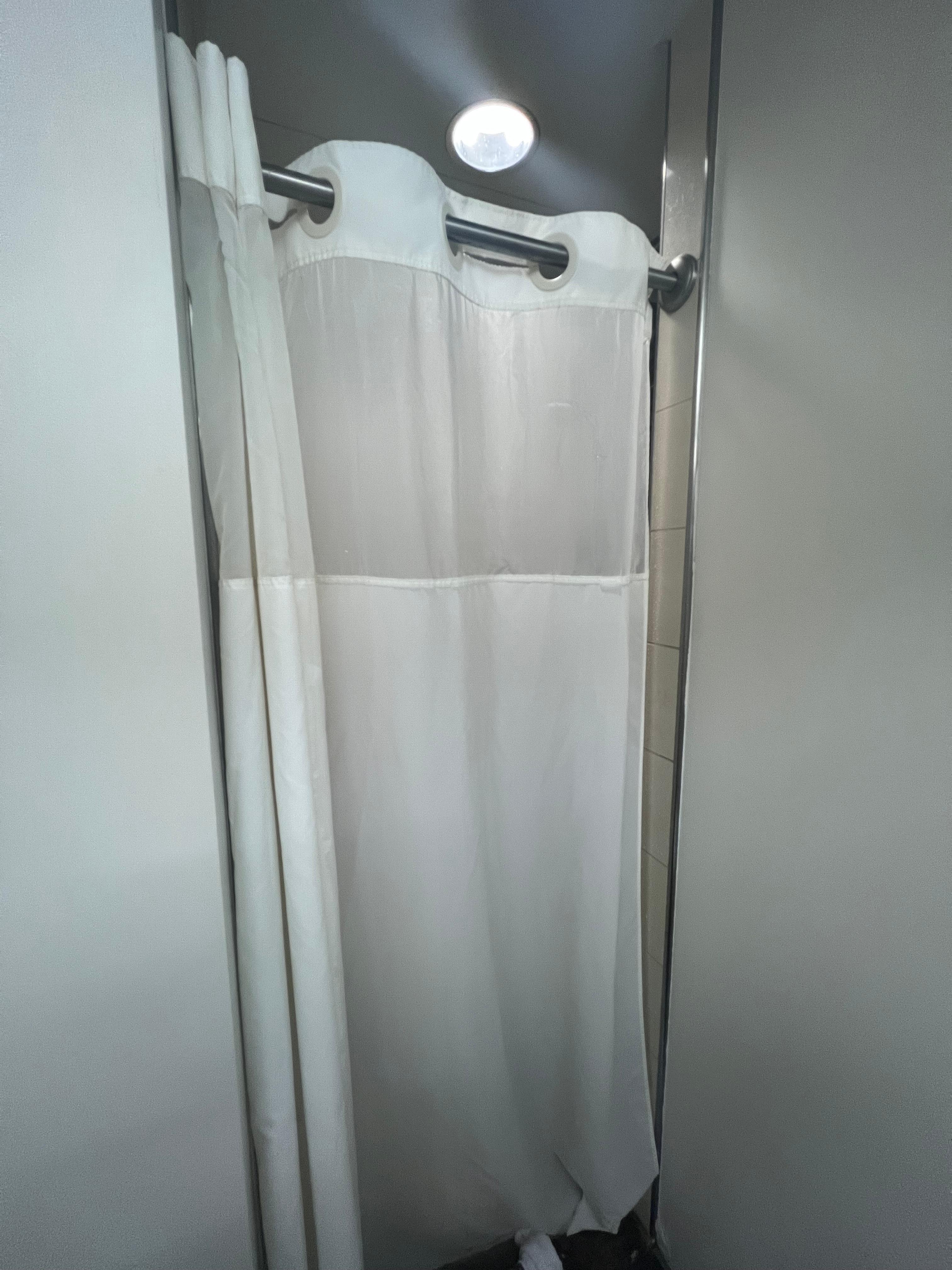 Tiny shower with a stained, disgusting shower curtain