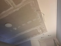 The unfinished ceiling in the bedroom with the loose wire.