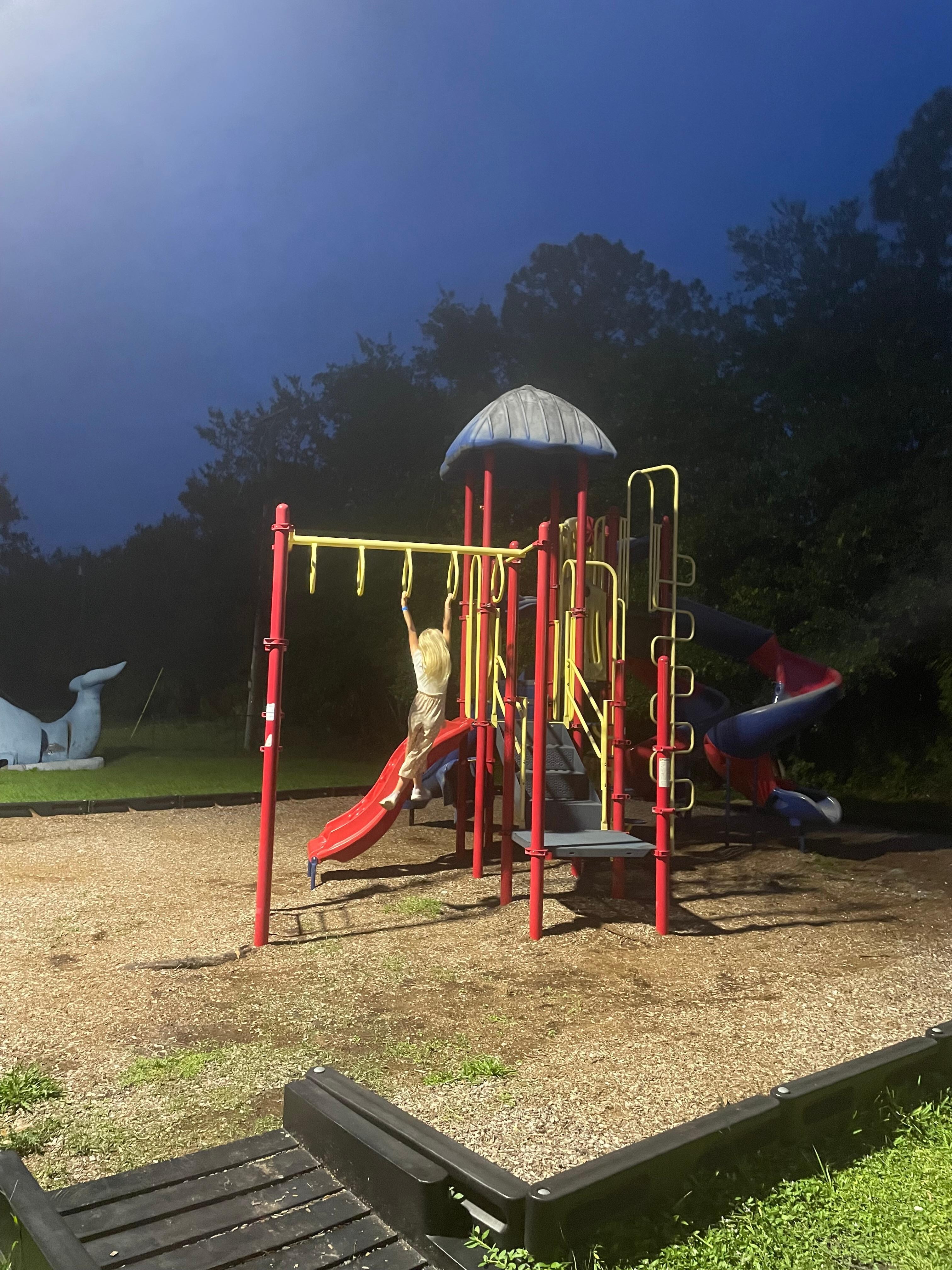 Playground area with a beach volleyball court and a basketball half court just behind this.