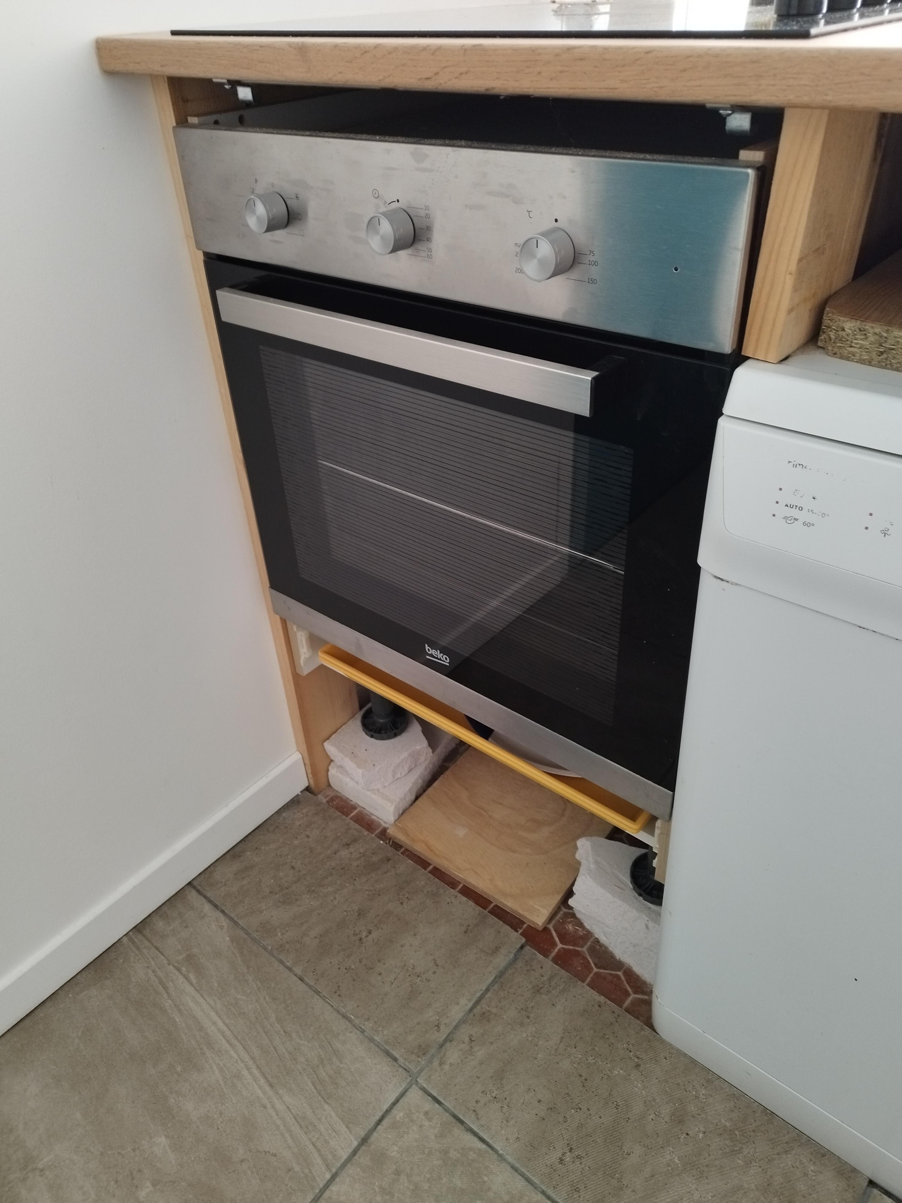 Four posé sur des parpaings. Encore des contre plaqué non fixé. Plaque induction ne pouvant fonctionner en même temps que le four sous peine de faire sauter le disjoncteur.