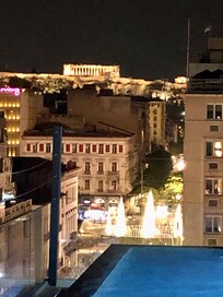 Rooftop pool at night with Parthenon in the distance (upper left)