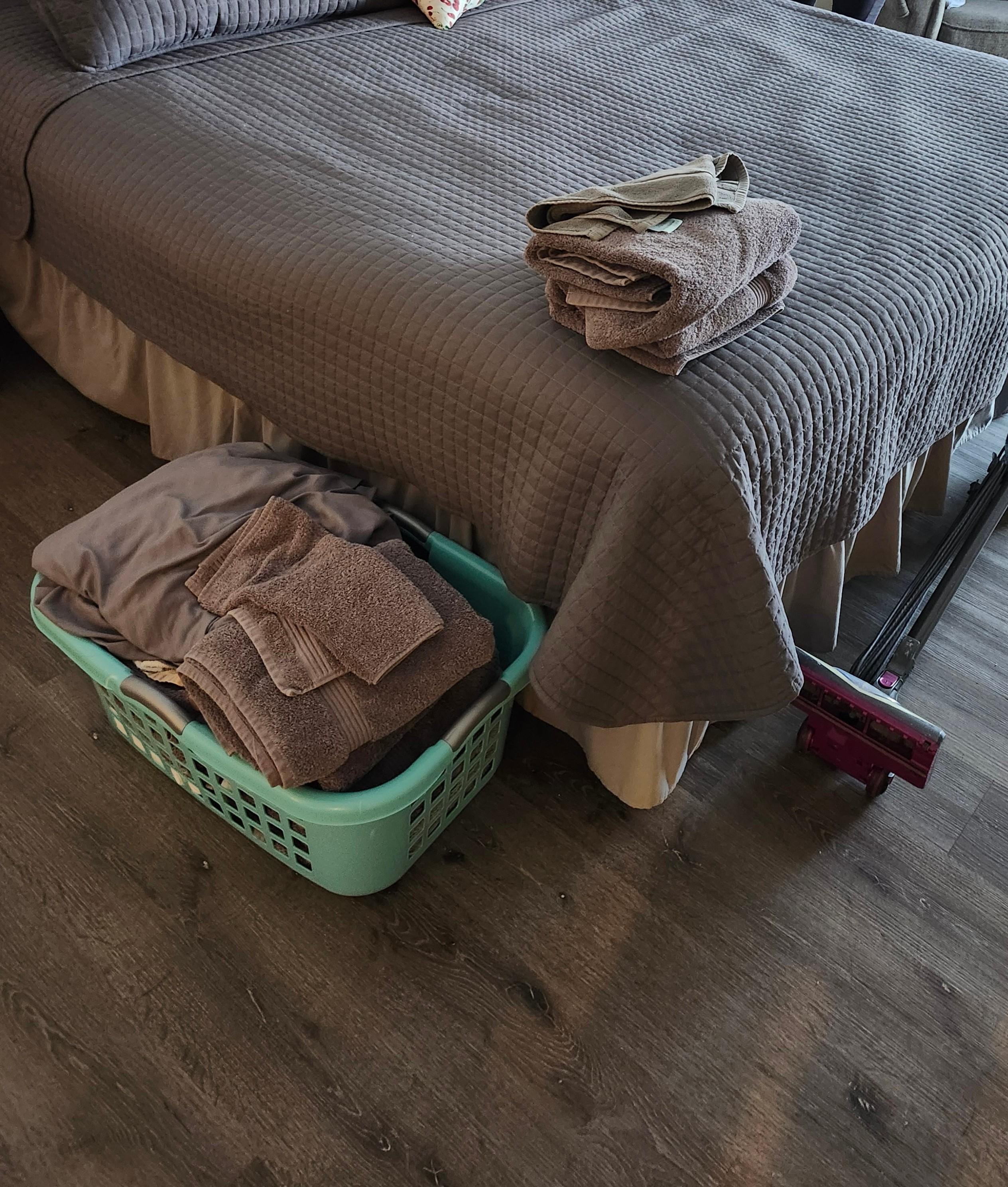 Dirty towels on the bed. Vacuum on the floor 