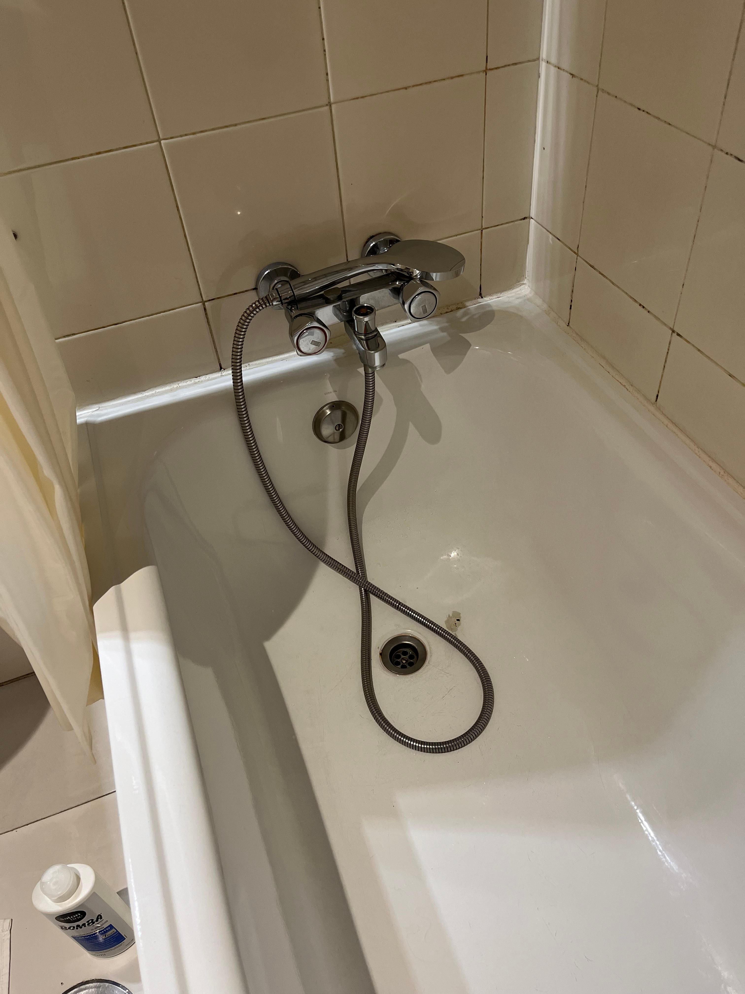 Banheira sem tampa e ducha apoiada na torneira.