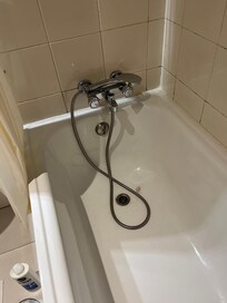 Banheira sem tampa e ducha apoiada na torneira.