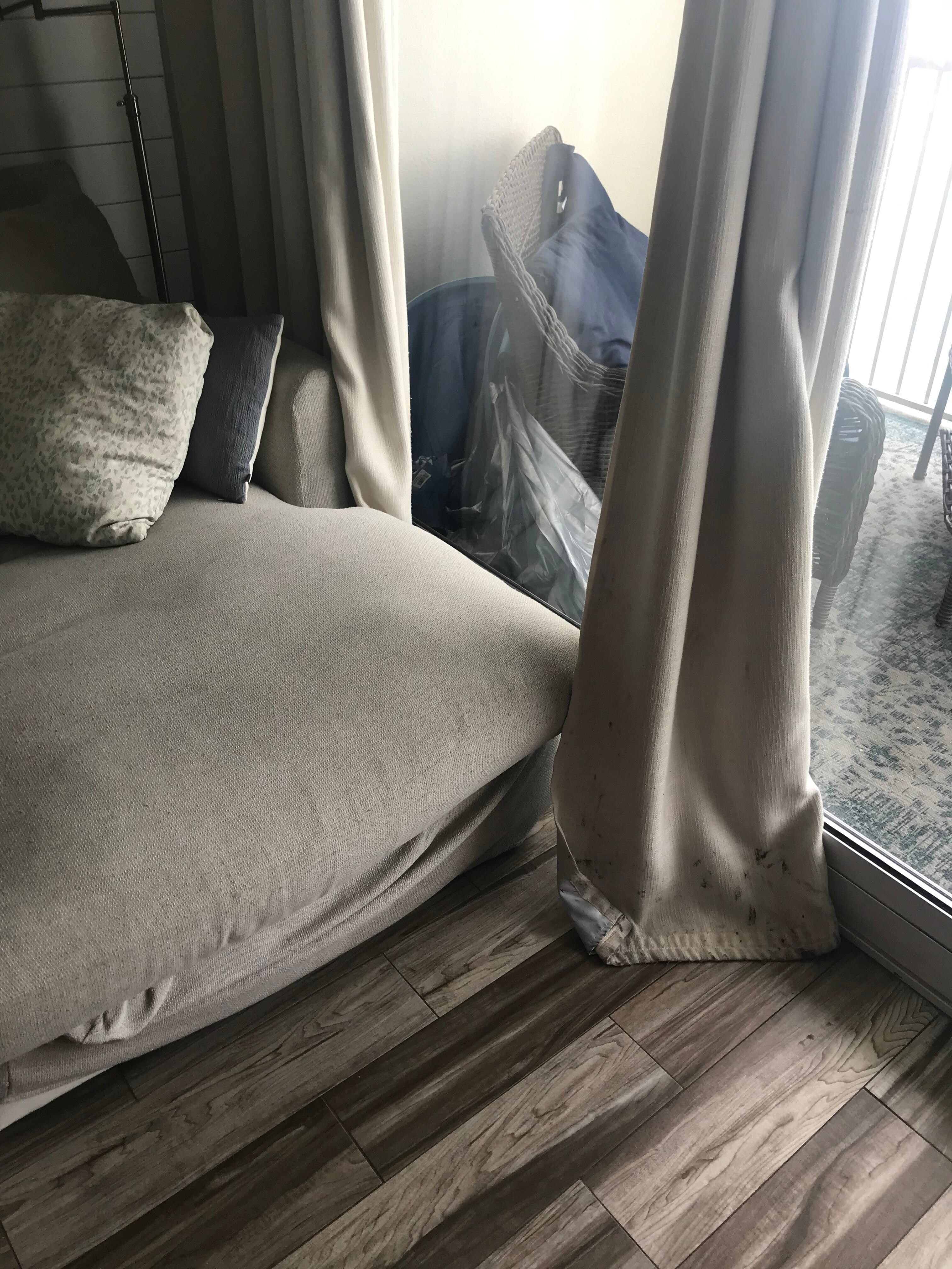 Living room furniture worn out; drapes filthy; trash stuffed behind balcony furniture