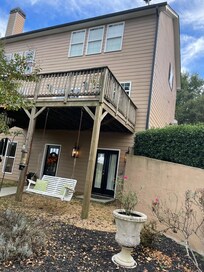 Rear view of house showing the basement underneath the deck - you walk behind the house down a steep hill into their backyard to enter the basement