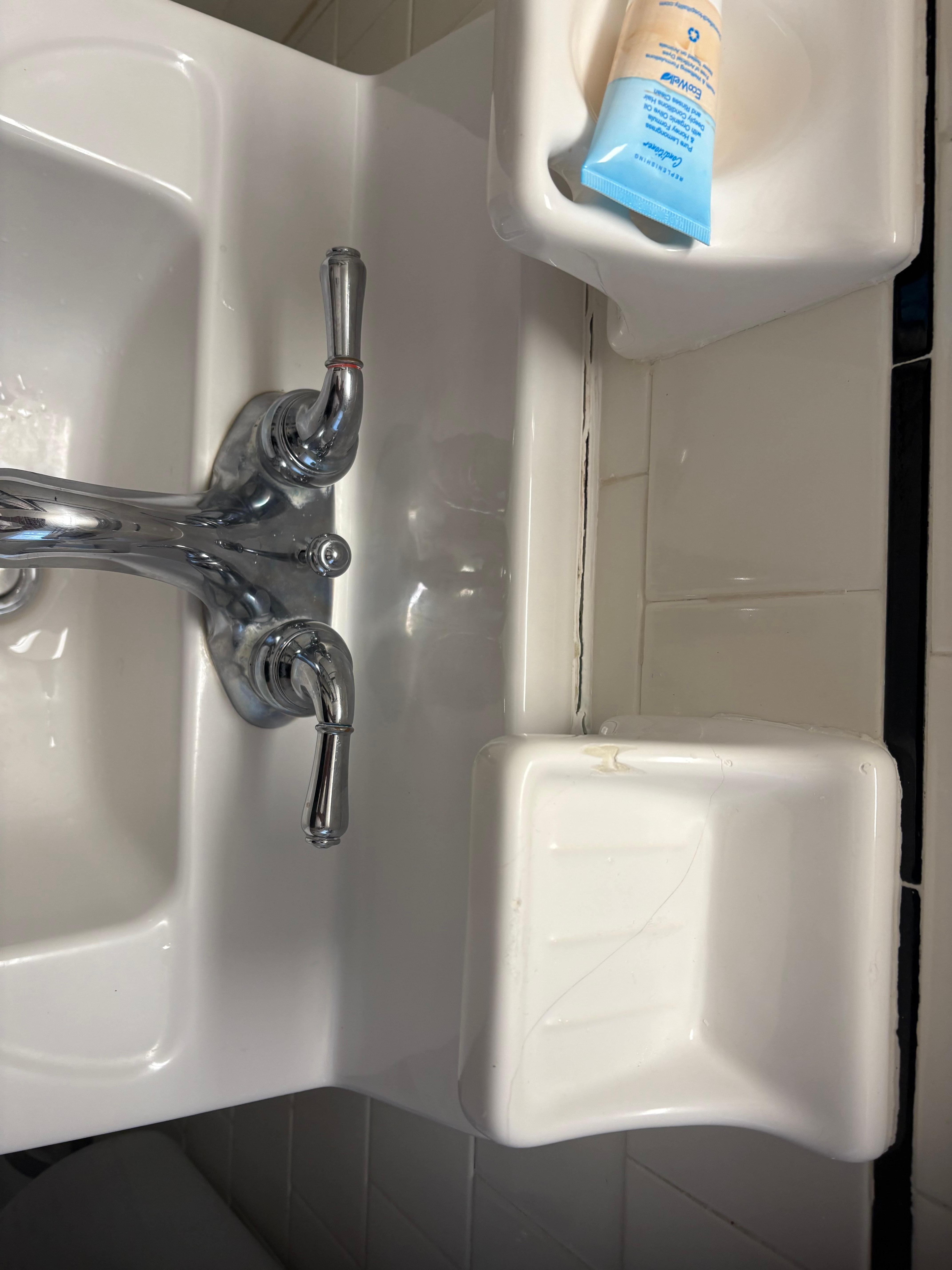 Busted soap holder glued on sink caulking open and towel rack coming off the wall 