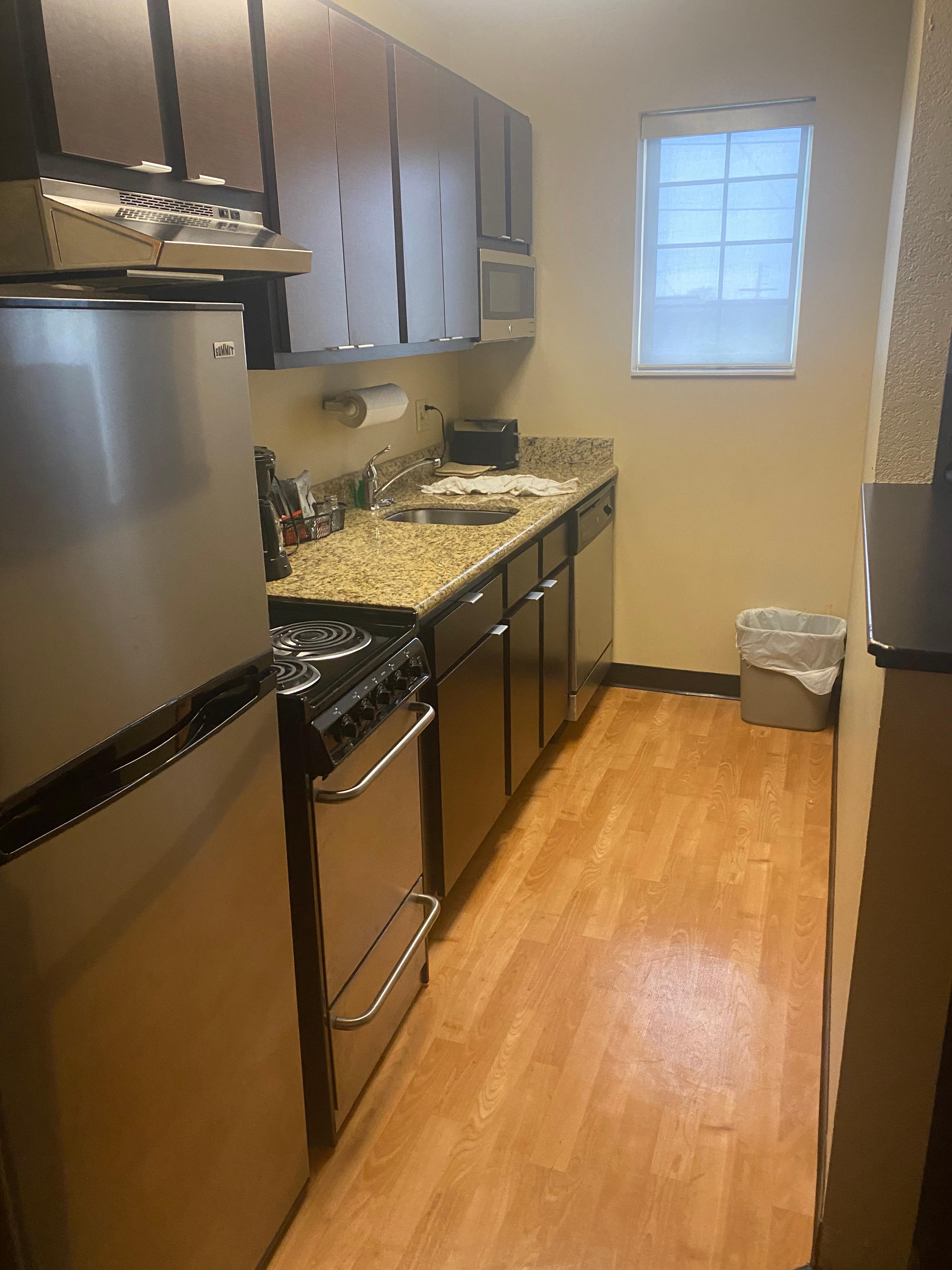 Kitchen with refrigerator, oven, dishwasher, dishes.