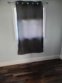 One curtain that does not cover the window totally. In the listing, this little room has a few chairs and table. It is actually empty.