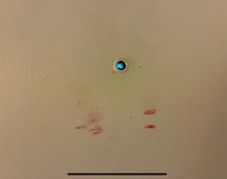 peep hole looking out door has either blood or lipstick stains