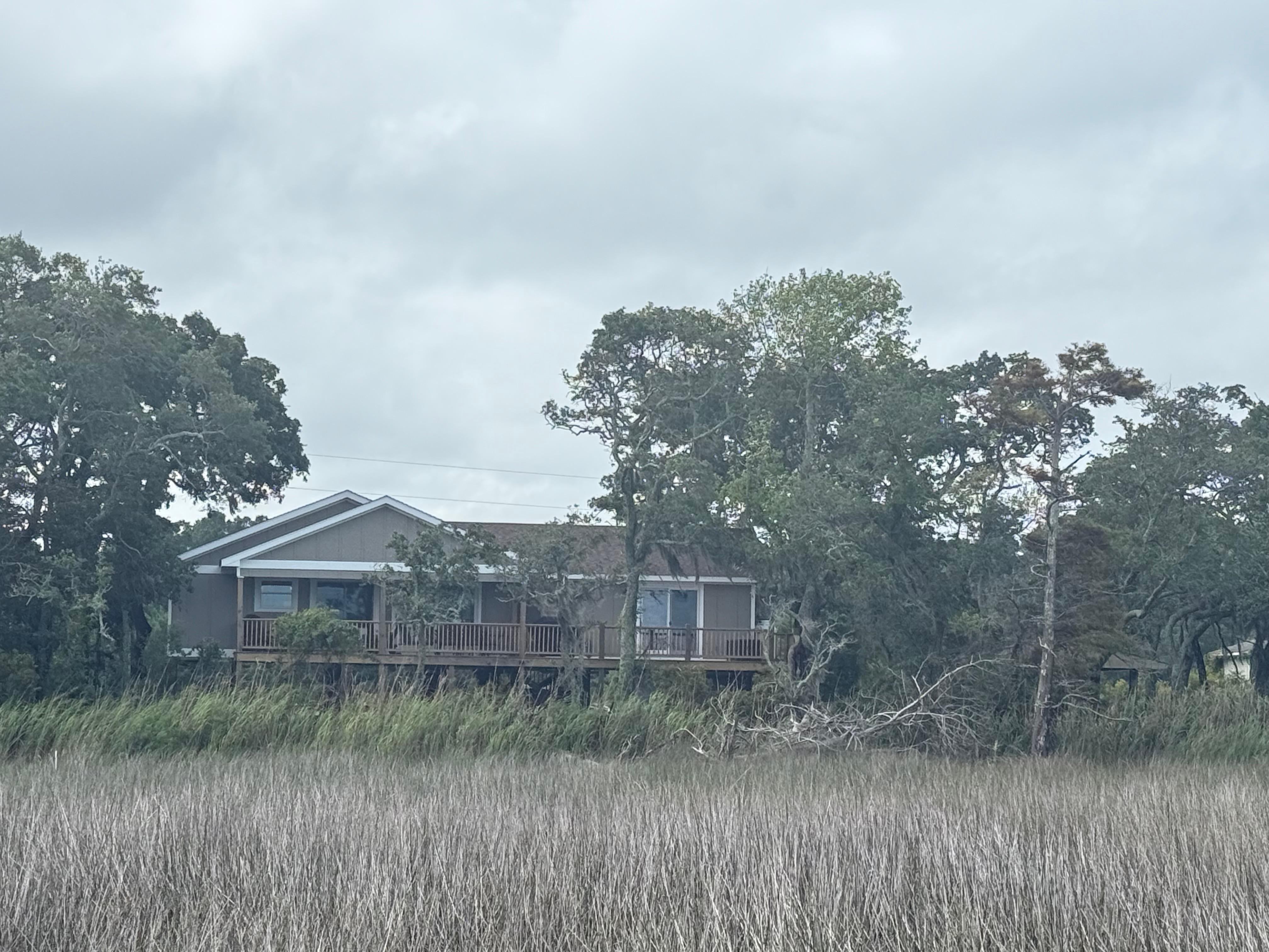 The house as seen from the sandy beach and across marshy inlets