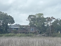 The house as seen from the sandy beach and across marshy inlets