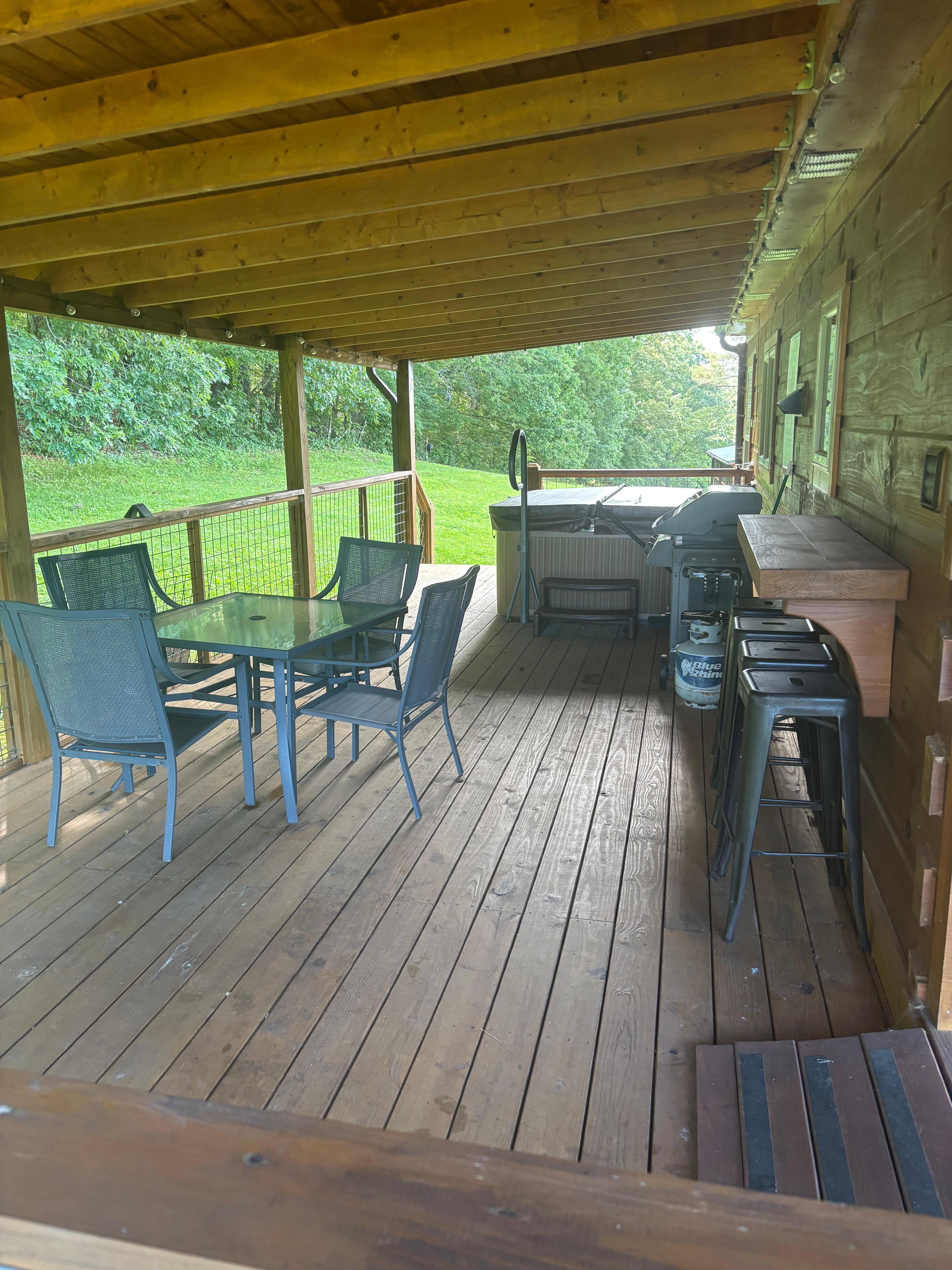 Covered long back deck that includes table & chairs ,hot tub , nice 2 burner Weber gas grill with propane tank an 4 stool counter top attached to cabin . 👍