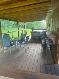 Covered long back deck that includes table & chairs ,hot tub , nice 2 burner Weber gas grill with propane tank an 4 stool counter top attached to cabin . đ