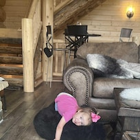Little Evelyn cozied up on the giant stuffed bear at Whistling Moose Lodge, claiming it as her new best friend and favorite snuggle spot. With a big smile and pink bow, she melted hearts right in the middle of the beautifully crafted log cabin