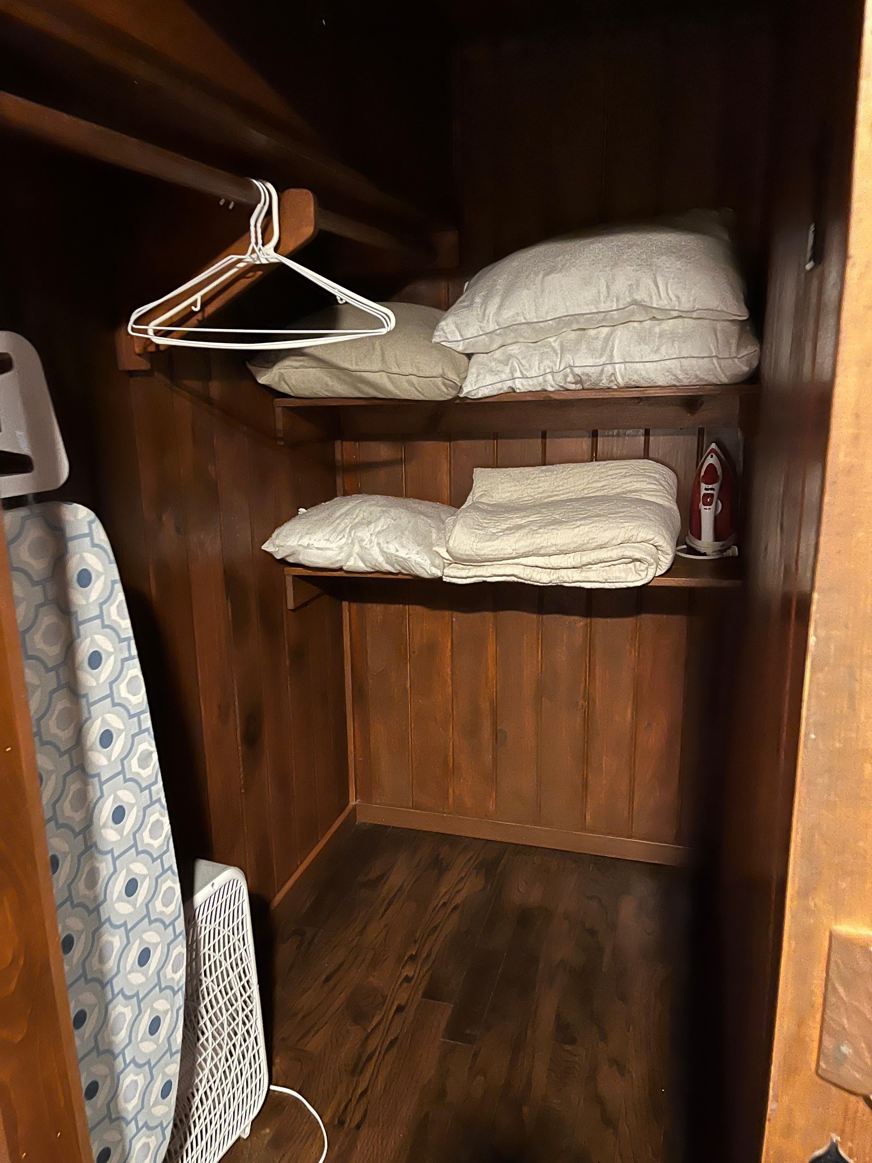 Comfortably sized closet with iron/ironing board.