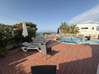 View from the table under the awning of the pool, sun beds and ocean view.