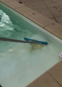 Brushing the step of the pool after it had been refilled still full of algae / grime