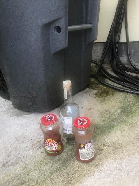 Half full alcohol bottle and garbage on driveway upon arrival. 