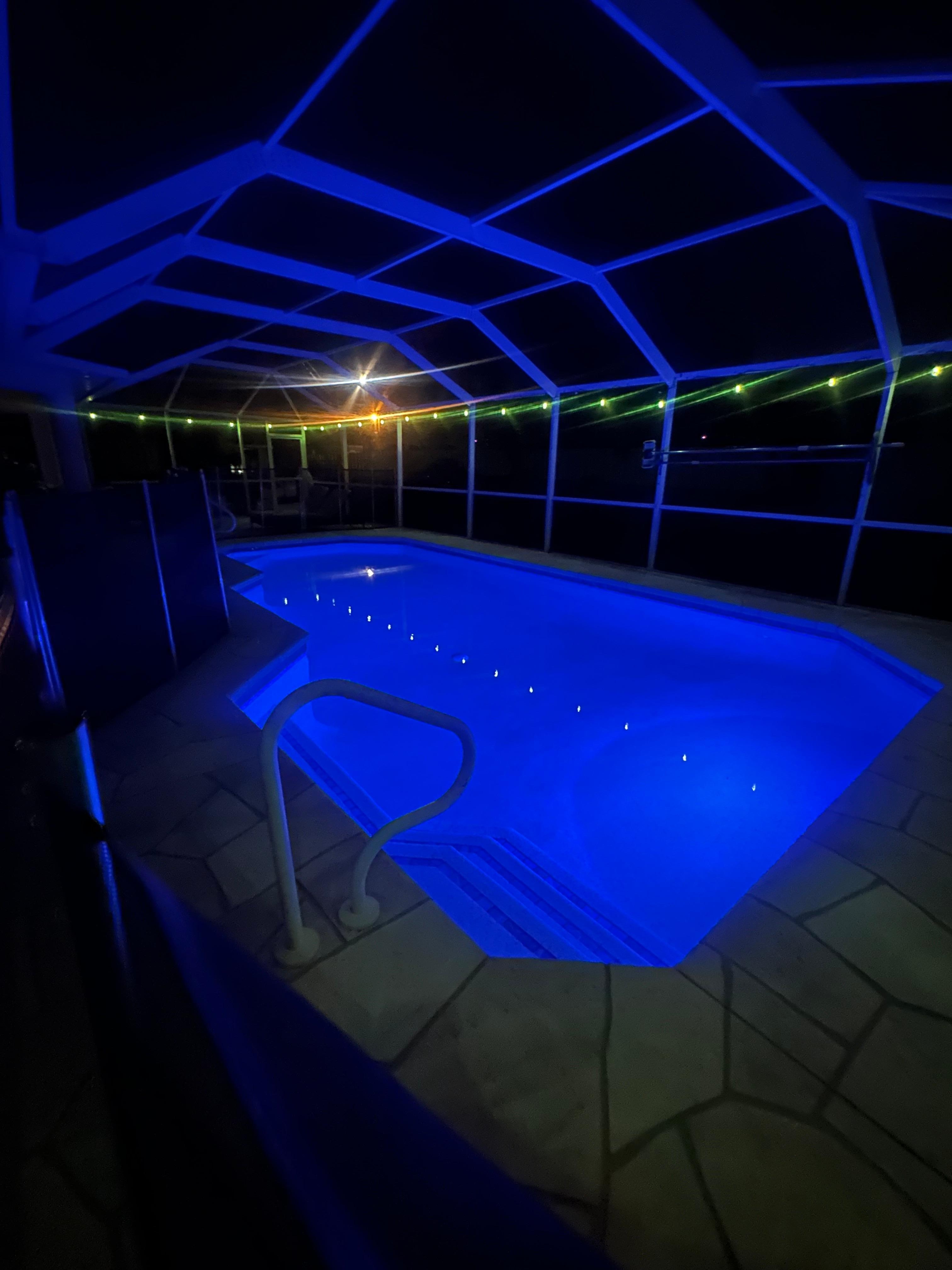 The pool at night with a light on inside of the pool
