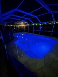 The pool at night with a light on inside of the pool