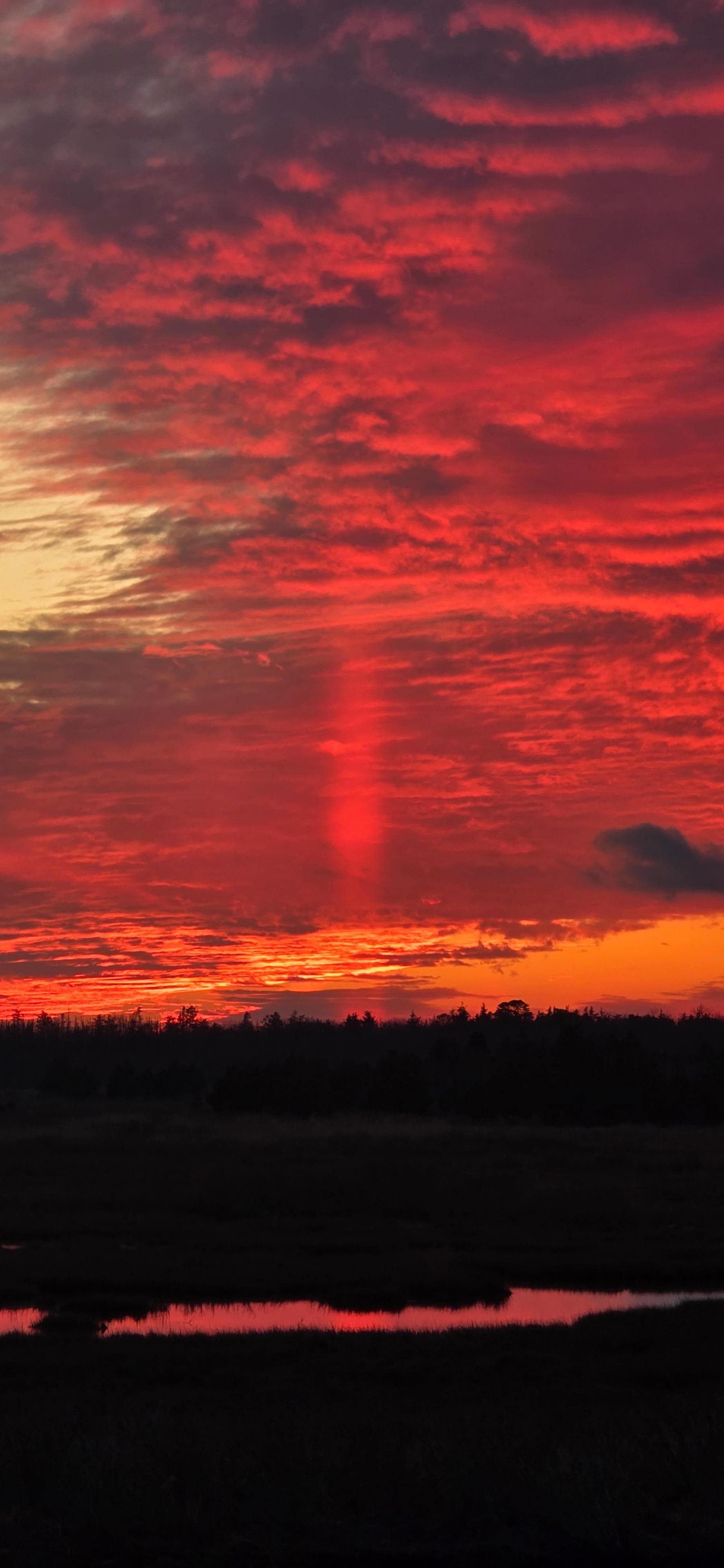 Taken from the dock in the backyard. I've only seen this solar pillar three or four times in my life ( scientific term crespicular pillar ray)