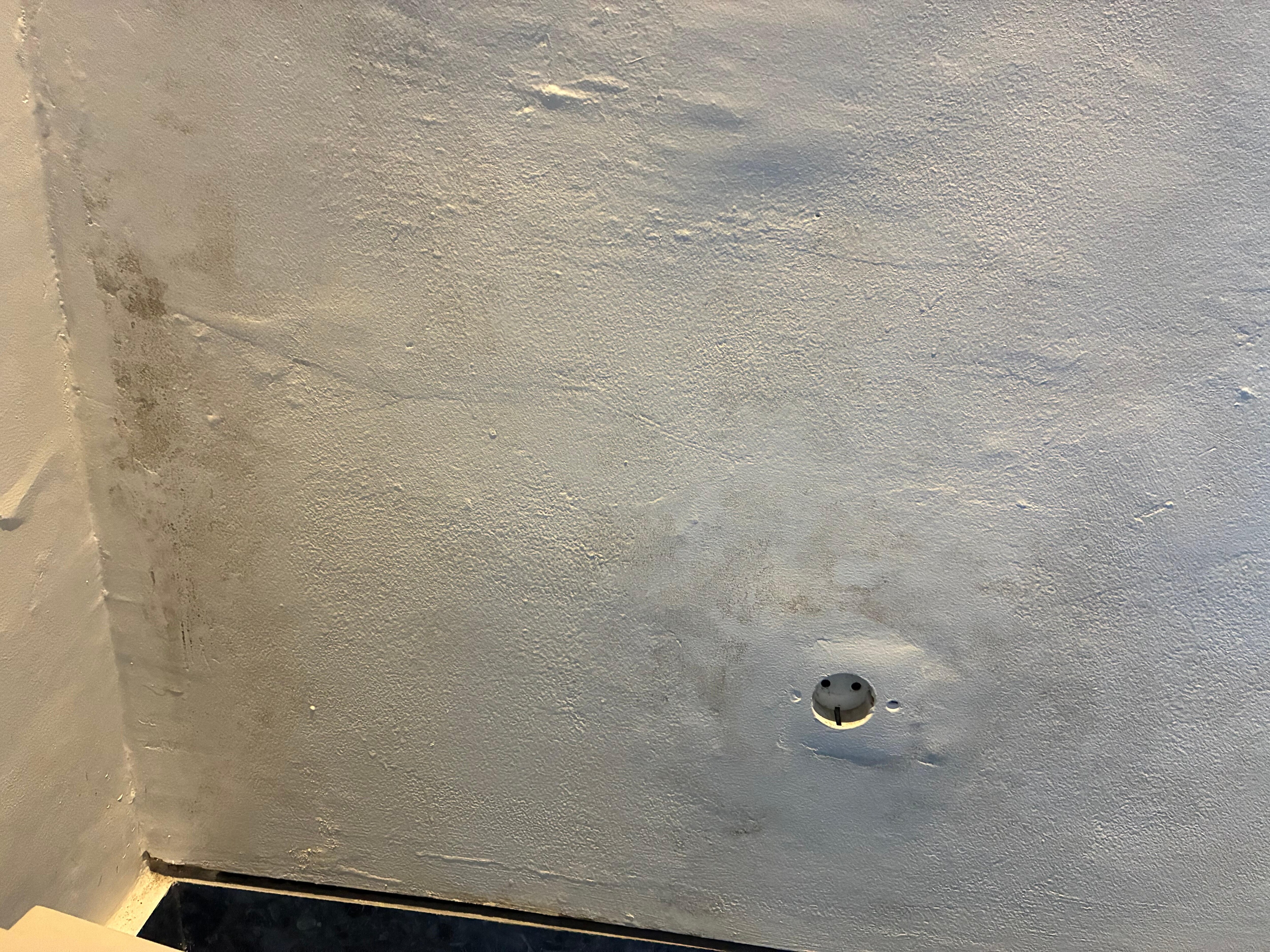 Damaged and mouldy wall in twin bedroom