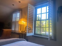 Cozy upstairs room with the sun shining through the beautiful shutters