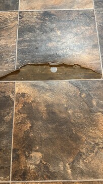 Torn floor right near fridge.. tripping hazard