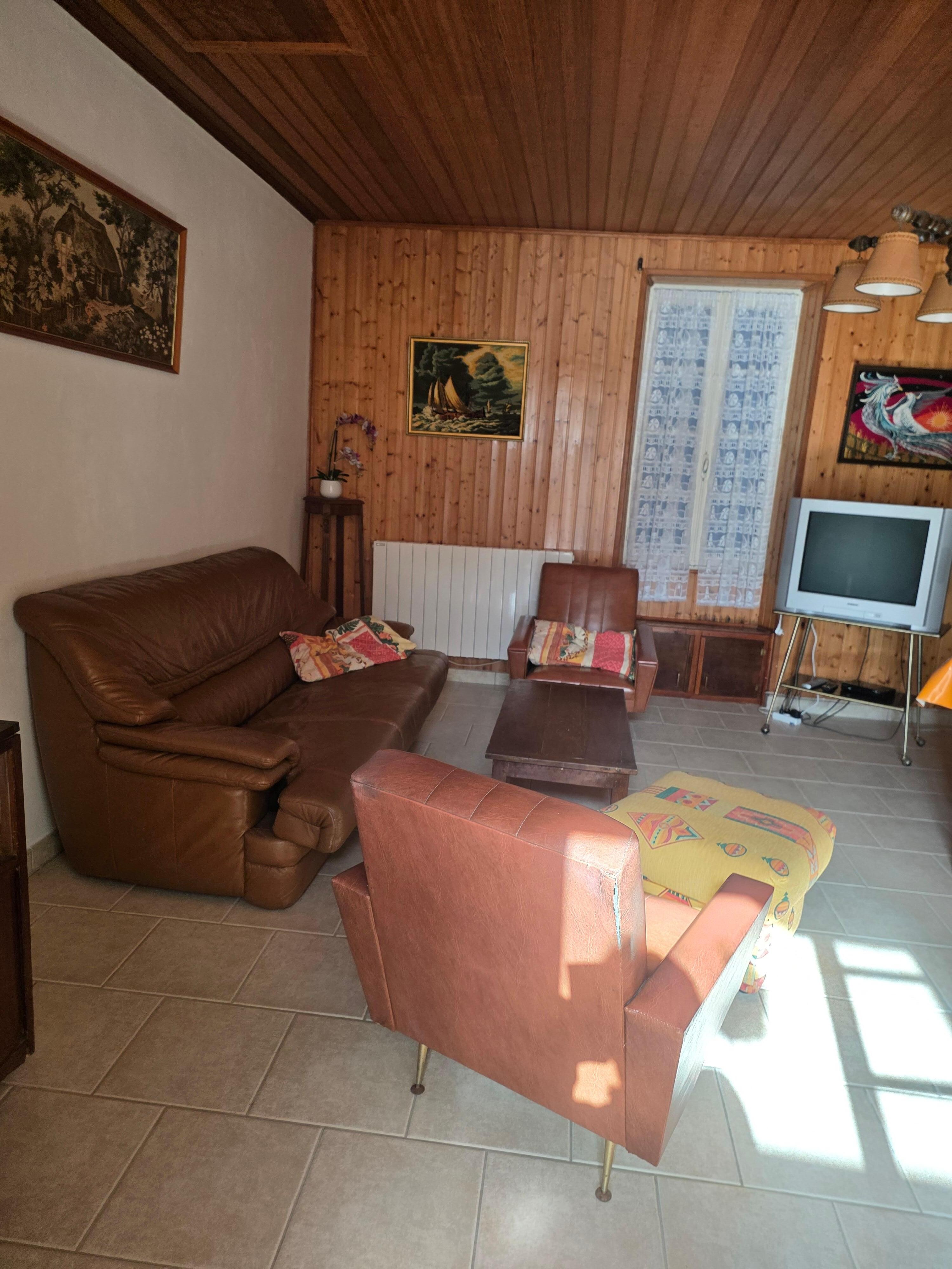 Salle à manger avec vieux meubles et vieille déco, vieille télé, canapé poussiéreux, sol sale