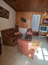 Salle à manger avec vieux meubles et vieille déco, vieille télé, canapé poussiéreux, sol sale
