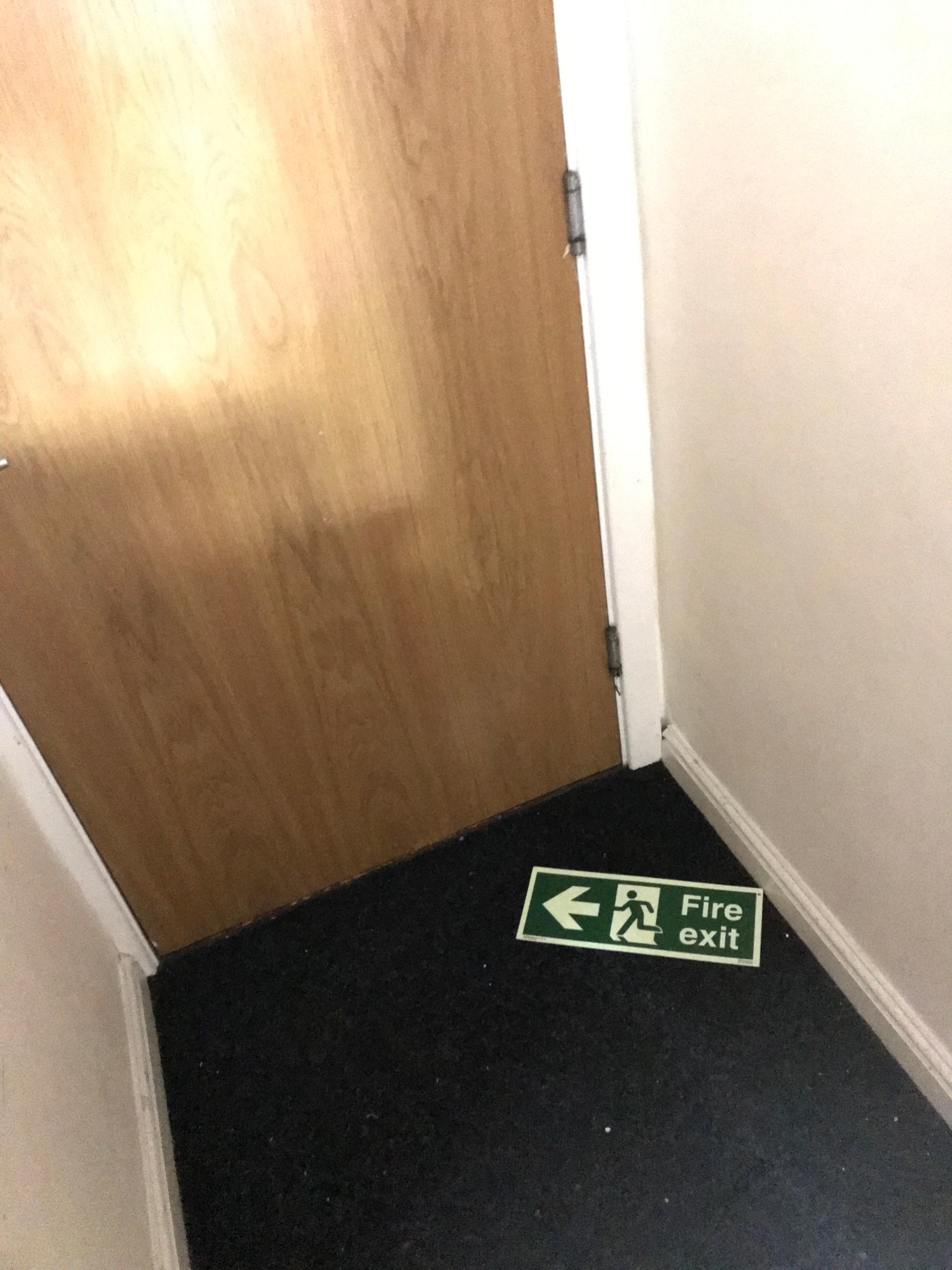 Fire exit sign on the floor leading to a locked door.