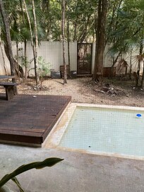 Garden pool area with broken loungers in the back, not cleaned and damaged decking