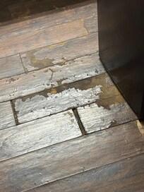 Flooring that is missing, has holes and finish is non existent. Also water on the floor by refrigerator.