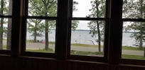 View from the front enclosed porch to the lake area with gazebo, kayaks and pontoon.