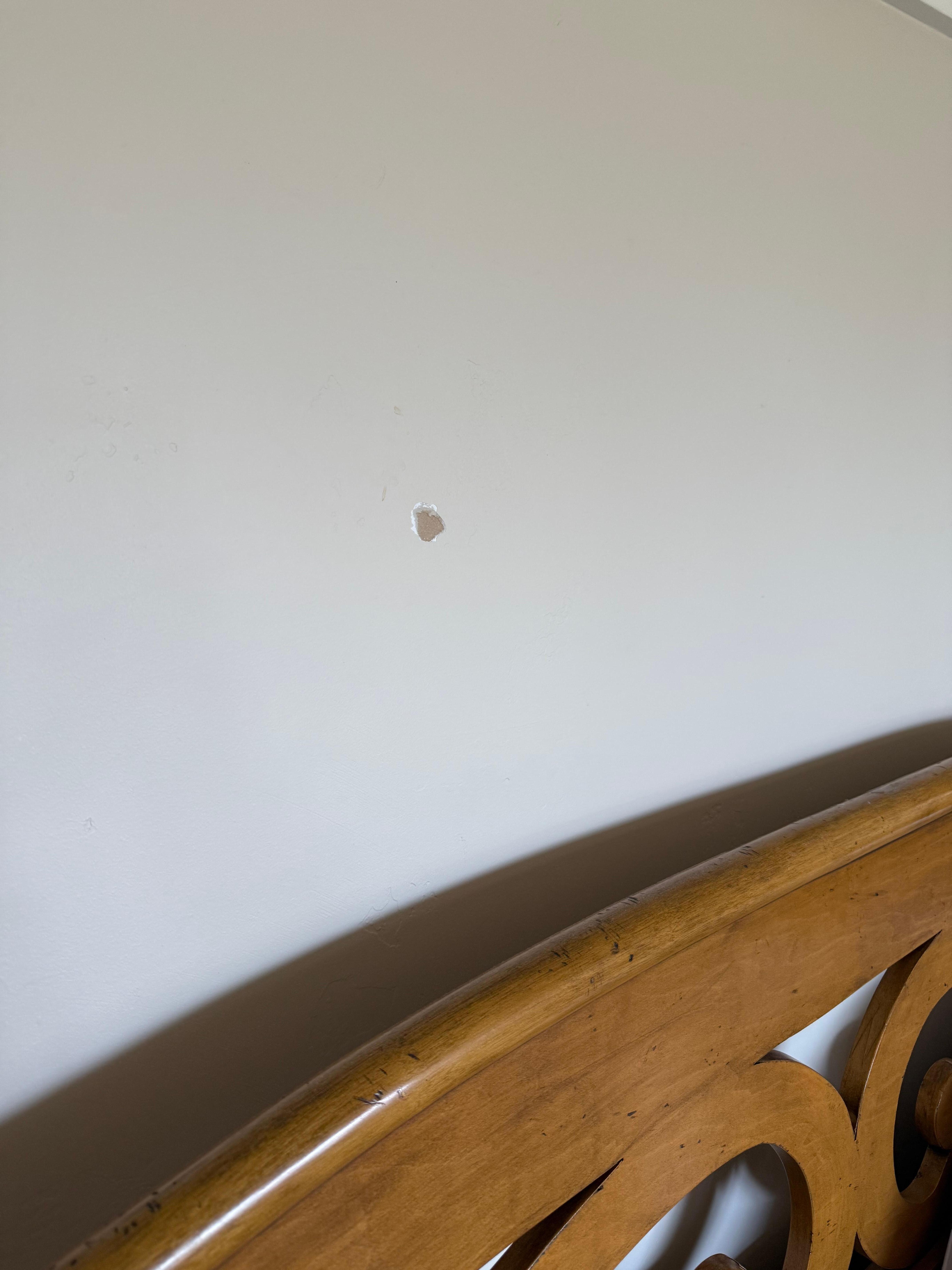 Hole in wall above bed. 