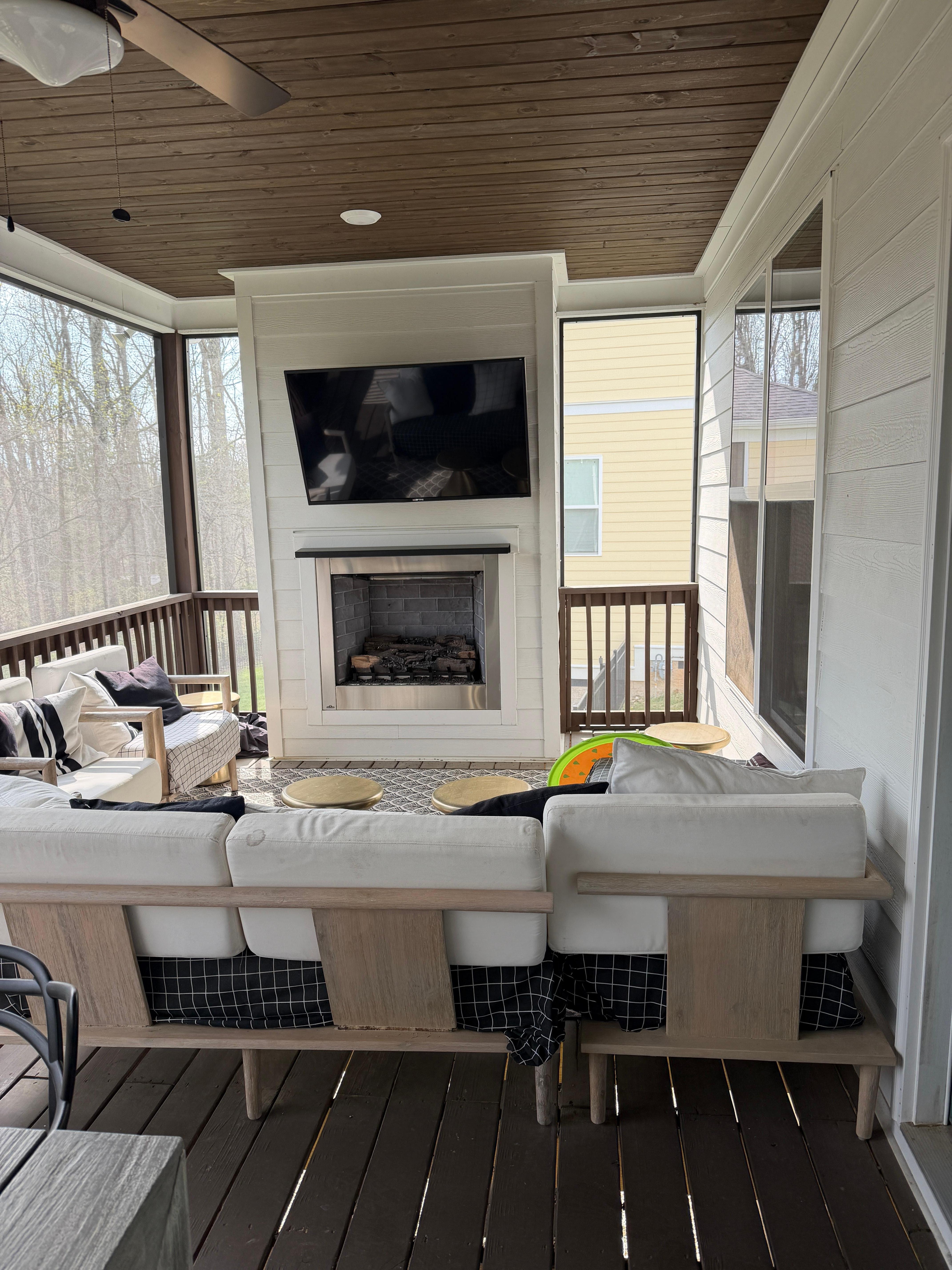 Screened porch area with a cozy fireplace and tv.