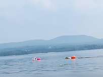 2 swimmers attached to colorful floats so motorboats see them while swimming.