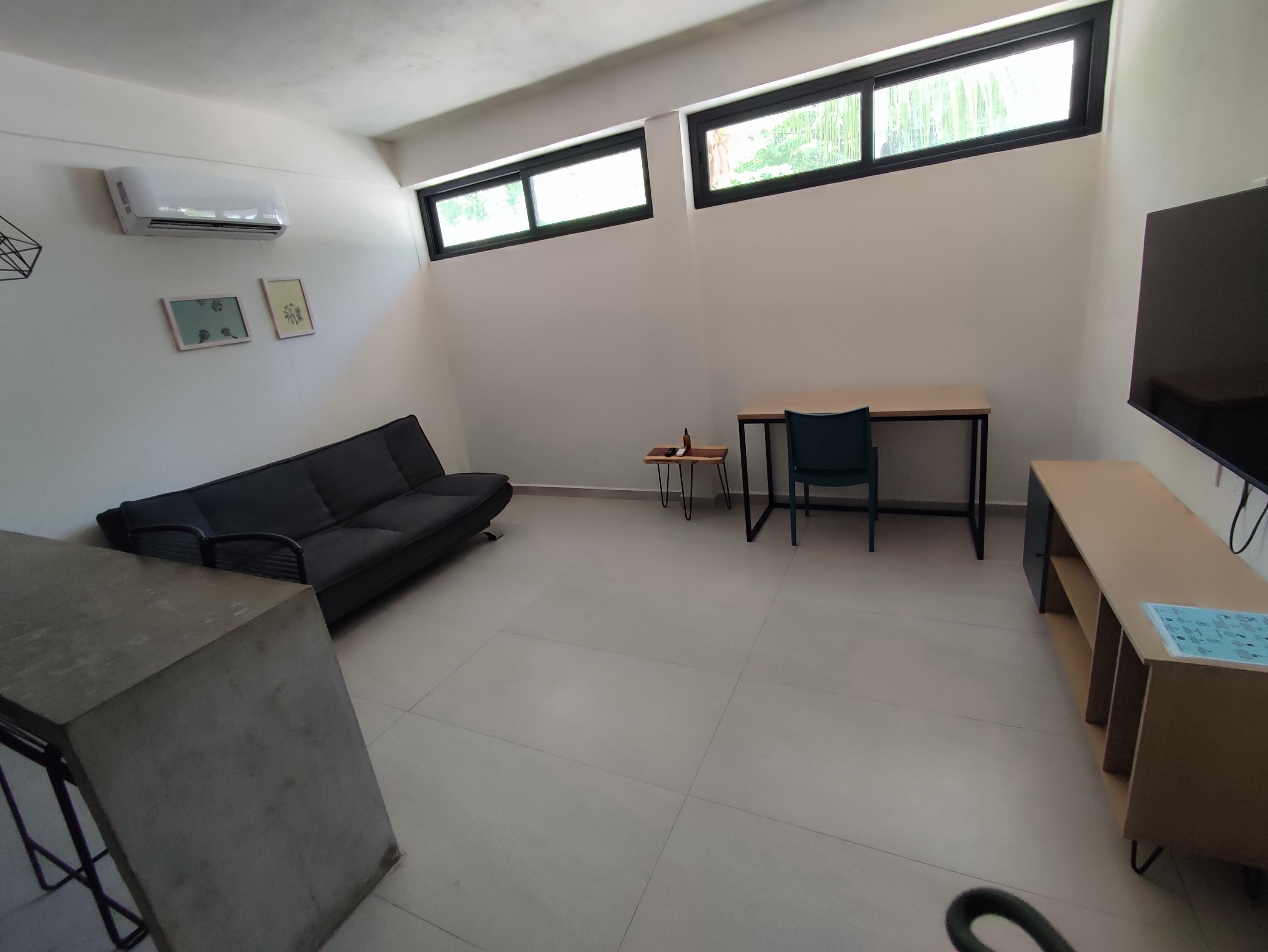 Sala de estar de buen tamaño, escritorio, sillón, aire acondicionado, pantalla con todas las amenidades.