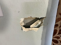 Large hole in wall beside the front door.