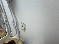 The outlet is exposed with no cover and is beside the sink.